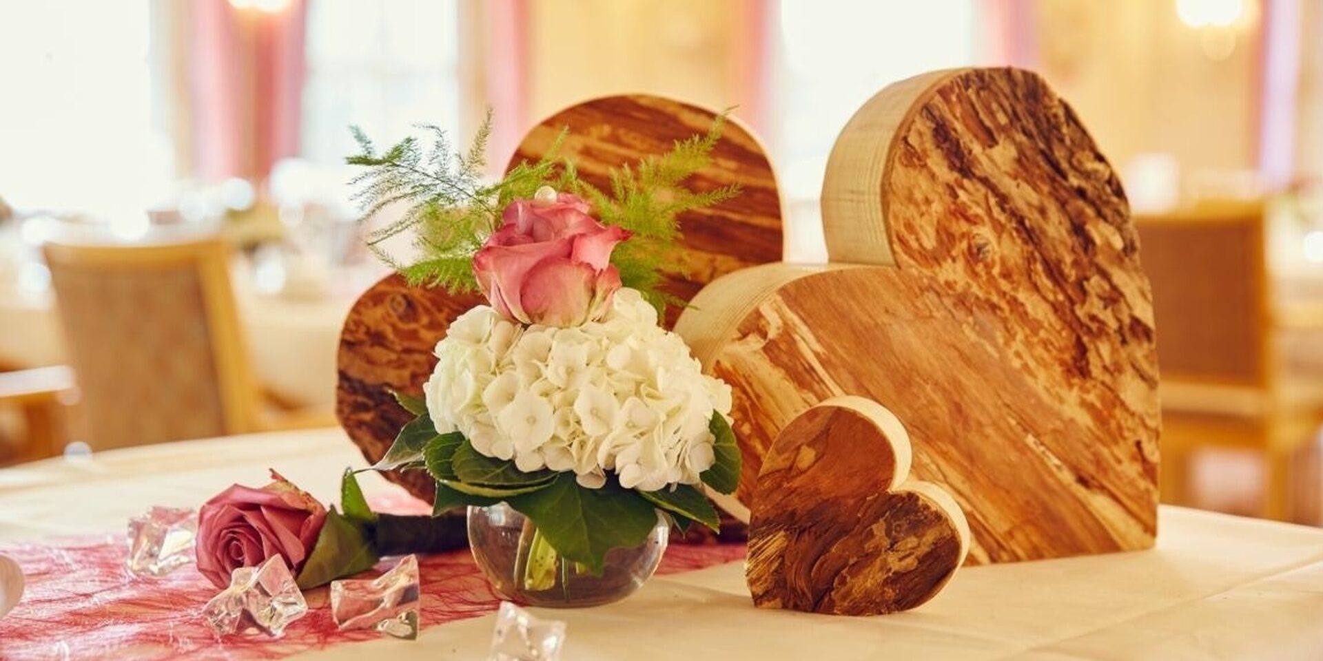 Tischdeko, bestehend aus Holz-Herzen und Blumen